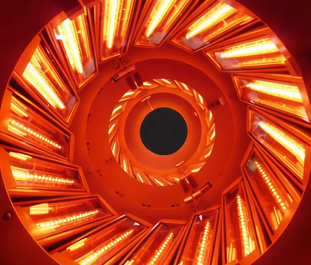 Interior view of a circular industrial infrared heating system glowing orange.